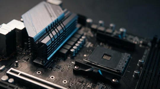 Vue rapprochée d'une carte mère avec son chipset refroidi par un dissipateur metallique, symbolisant le controle et l'optimisation d'une configuration informatique