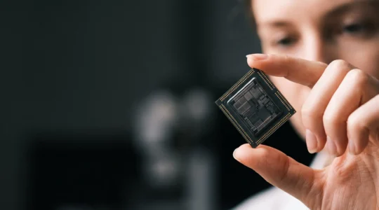 Gros plan artistique sur un processeur tenu à la lumière, symbolisant l'analyse et la compréhension d'une fiche technique CPU